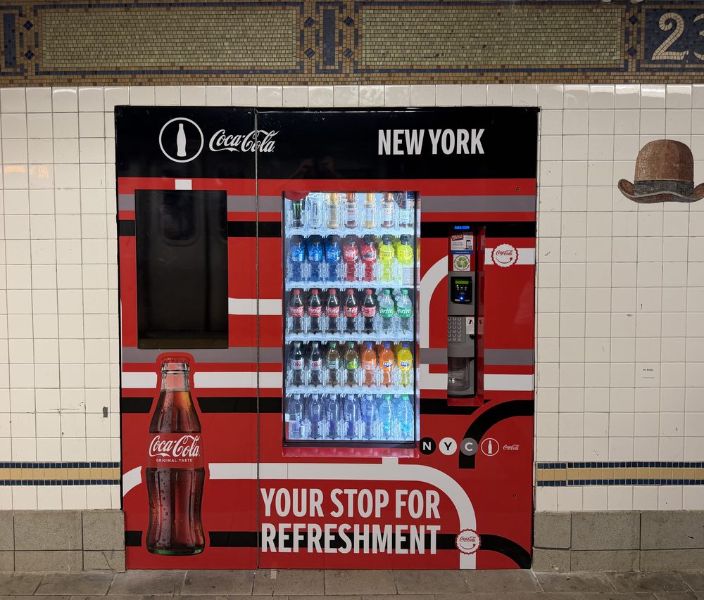 Coca-Cola-branded automated retail machine set into the original tile wall of the 23rd Street-Broadway subway station